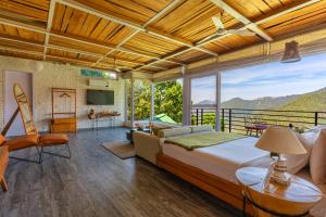 a bedroom with a large bed and a balcony at Seclude Ramgarh Cliff's edge in Rāmgarh