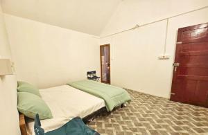a bedroom with a bed and a wooden door at The Canvo Vattavada Private Cottages in Vattavada