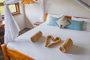 a bed with two towels in the shape of hearts at Mwazaro Beach Lodge in Shimoni +78 photos