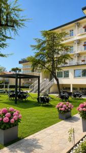 un parque con mesas y flores frente a un edificio en Hotel Amedea, en Cervia