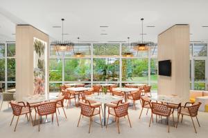 a dining room with tables and chairs and windows at Danubius Hotel Annabella in Balatonfüred