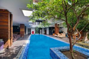 a pool in the middle of a building with a tree at Palette Hotel Seminyak in Seminyak