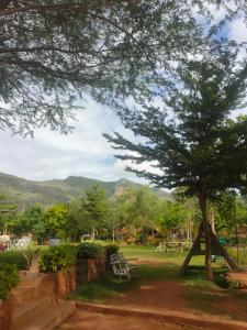 a park with a tree and a bench and mountains at Sere n' Lukundo Park & Camping Services in Voi