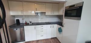 a kitchen with white cabinets and stainless steel appliances at De Weide Blick in Tuitjenhorn +24 photos