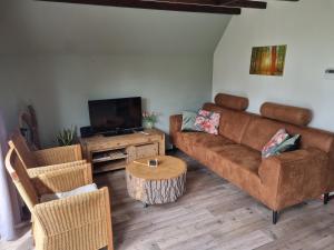 a living room with a couch and a tv at De Weide Blick in Tuitjenhorn