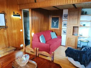 a living room with a red couch and a table at Maison Seguret 50mt from sky lifts in Sauze dʼOulx