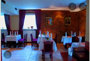 a restaurant with white tables and chairs and a brick wall at Wilcze Schronisko in Czerniki