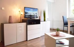 a living room with a tv on a white cabinet at GUWO Gästewohnung Goethestraße 82d in Guben