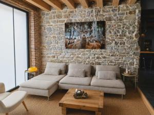 a living room with a couch and a stone wall at 3 Waters Spa - Private Spa with Jacuzzi, Sauna & Hammam in Winenne +18 photos