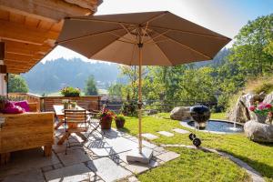 a patio with an umbrella and a grill at Ferienwohnungen Fendl in Fischbachau