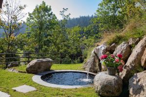 a pond with a waterfall and flowers in a yard at Ferienwohnungen Fendl in Fischbachau