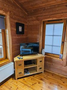 a living room with a television on a wooden cabinet at Otter lodge, Lakeside Lodges in Dulverton