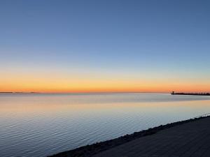 a view of the ocean at sunset with a pier at Moderne Doppelhaushälfte - perfekt zu zweit in Dagebüll