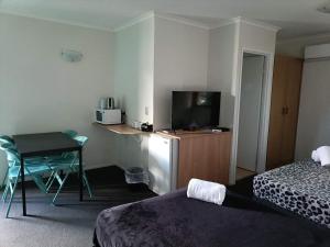 a hotel room with a bed and a desk with a television at Motel in Nambour in Nambour