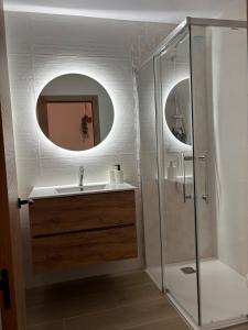 a bathroom with a sink and a shower with a mirror at Alaire Alojamiento in Algodonales
