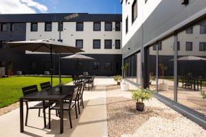 a patio with tables and umbrellas outside of a building at Mayor Pension in Komárno