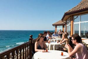 a group of people sitting at tables at a restaurant overlooking the ocean at Otel Ustabaş in Hopa