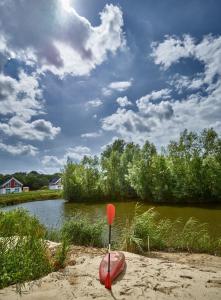 a red kayak sitting in the sand next to a lake at Ferienhaus Pier 85 in Nordhorn