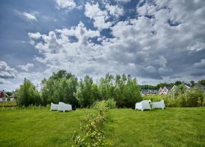 two white chairs in a field with a cloudy sky at Ferienhaus Pier 85 in Nordhorn