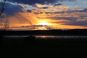 a sunset over a lake with the sun setting at Ferienwohnung Jargow 1 - Alt-Reddevitz in Alt Reddevitz