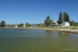 a large body of water with houses in the background at Ferienwohnung Jargow 1 - Alt-Reddevitz in Alt Reddevitz +8 photos