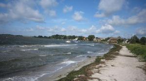 a beach with waves in the water and houses at Ferienwohnung Jargow 1 - Alt-Reddevitz in Alt Reddevitz