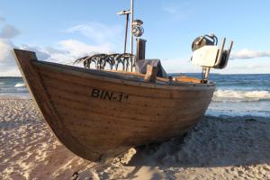 a wooden boat sitting on the sand on the beach at Ferienwohnung Jargow 1 - Alt-Reddevitz in Alt Reddevitz