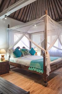 a bedroom with a canopy bed with blue pillows at Villa Karma Legian in Legian