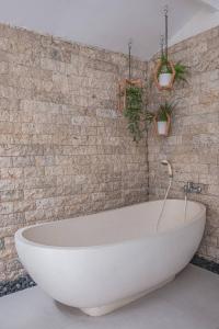 a bath tub in a bathroom with a brick wall at Villa Karma Legian in Legian