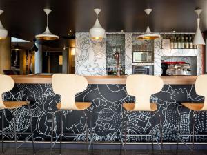 a bar with a black and white wall with stools at ibis Pau Lescar in Lescar