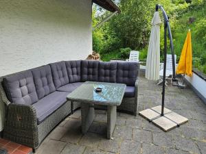 a couch on a patio with a table and an umbrella at Schöne Aussicht am Eifelsteig in Monschau