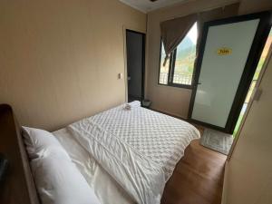 a bedroom with a white bed and a window at Thanh Thao Hostel - HaGiang Loop Tour in Làng Lap +3 photos