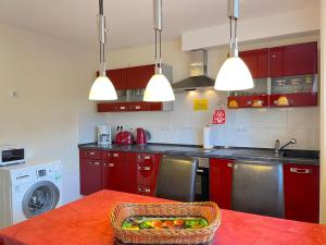 a kitchen with red cabinets and a basket of fruit on a table at Zimmer & Ferienwohnung Steuer in Leippe