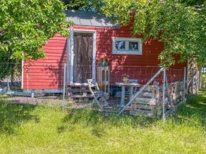 a red house with a table and a chair in front of it at Tiny House auf der Alpaka Farm in Rubkow