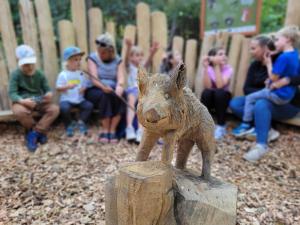 a statue of a dog on top of a wooden stump at Bungalow THEA in Langhagen