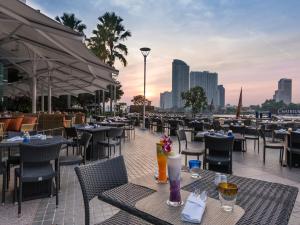 a restaurant with tables and chairs on a patio at Chatrium Hotel Riverside Bangkok in Bangkok