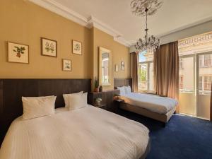a hotel room with two beds and a chandelier at Hotel Botaniek in Bruges