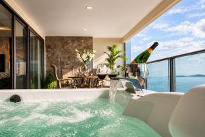 a bath tub with a bottle of wine in a room at The Elysium Prațumnak Pattaya - By SHG in Pattaya South