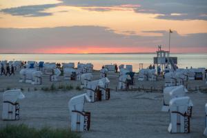 a group of chairs on the beach at sunset at 216 große Ferienwohnung Schwalbennest in Wittmund