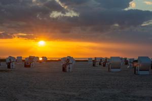 a group of chairs on the beach at sunset at 216 große Ferienwohnung Schwalbennest in Wittmund