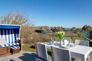 a white table with chairs and a vase of flowers at Haus Meerblick in List
