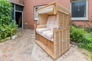 a wicker couch in a wicker shelter in front of a building at Ferienwohnung Eulennest, 35230 in Schwerinsdorf