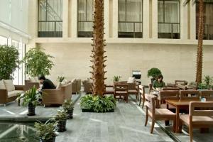 a lobby with tables and chairs and palm trees at Wanshang Garden Hotel in Beijing