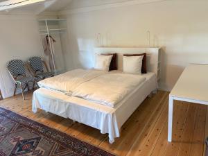 a bedroom with a large bed with white sheets at Købmandsgården, Ballen in Ballen