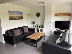 a living room with two leather couches and a coffee table at De Duinrand in Oostkapelle