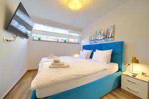 a bed with a blue headboard in a bedroom at VILLA SOLIS LACUS modernes Apartment - privater beheizbarer Pool- Klimaanlage - private Parkplätze in Njivice