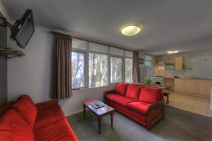 a living room with a red couch and a table at Kosciusko Tourist Park in Jindabyne