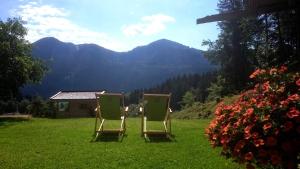 two chairs sitting on a lawn with mountains in the background at Ferienwohnungen Kimpfbeck, Kreuth-Schärfen in Kreuth