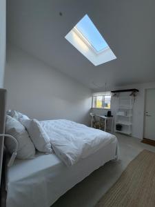 a bedroom with a white bed with a skylight at Købmandsgården, Ballen in Ballen +161 photos