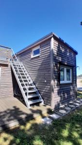 a wooden house with a staircase on the side of it at Tiny Haus C235 Wacholderdrossel in Groß Kordshagen +9 photos